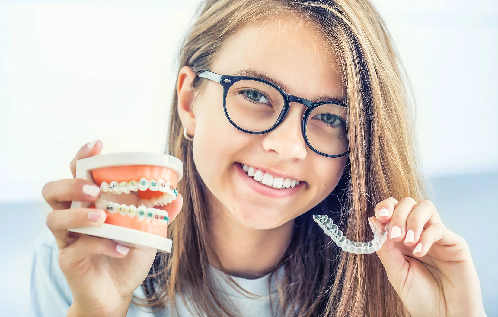 Girl holding traditional braces and Invisalign